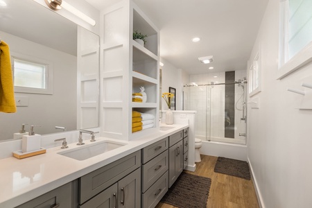 Spacious guest house bathroom with walk-in shower, open shelving, and spa-like style for ultimate comfort.
