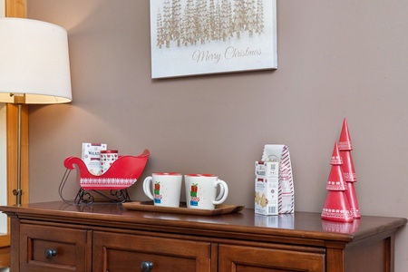 Side table with holiday decorations and mugs, adding charm to the cozy space.