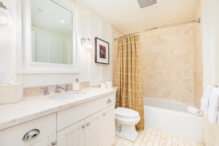 The shared guest bathroom offers a clean, modern design with a shower-tub combo and vanity for added comfort.