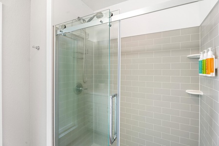 Contemporary walk-in shower with clean subway tile and sliding glass door.
