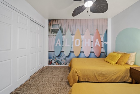 Cozy twin bedroom with surf-inspired wall art, creating a fun and relaxing beachside retreat.
