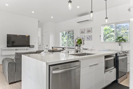 The kitchen features modern appliances, a sleek island with bar seating, and pendant lighting