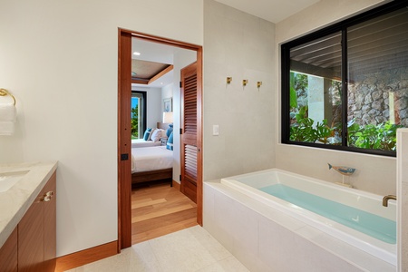 Relaxing bathroom featuring a deep soaking tub with a private garden view.