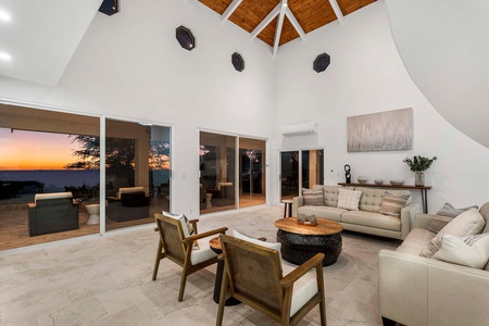Gather in the airy living room where high ceilings, plush seating, and garden views create a calming retreat.