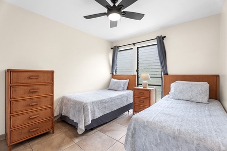 Second bedroom with two twin beds, ceiling fan, and natural light—perfect for kids or traveling companions.