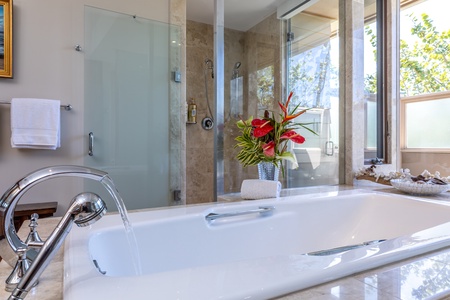 Indulge in your private spa sanctuary with a luxurious soaking tub, elegant rainfall shower, and tropical blooms creating the perfect retreat.