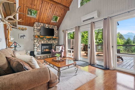 Relax in the cozy living room with a stone fireplace and doors that open to the deck.