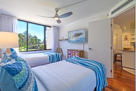 Garden-view guest room at Kaanapali Shores 213, with cozy beds and a TV, perfect for a peaceful night in.