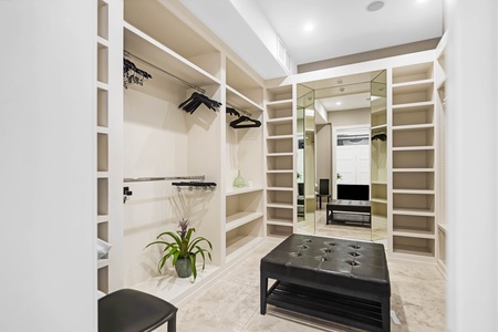 Spacious walk-in closet with seating and custom built-ins.
