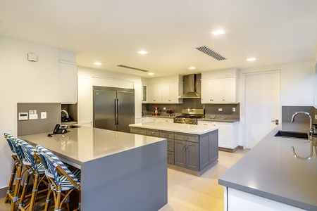 Modern kitchen featuring a large stainless steel refrigerator, and a spacious island with seating, perfect for casual dining and entertaining.