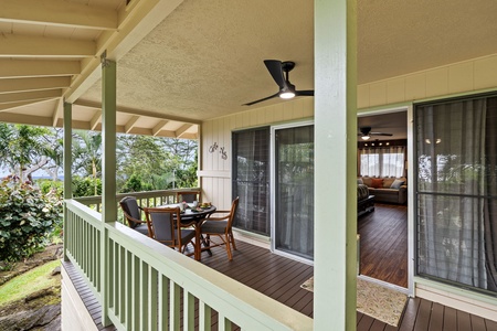 Relax on your private covered balcony, where a cozy dining set awaits and lush tropical gardens frame peaceful moments. The ceiling fan keeps you cool as you unwind with views of the surrounding greenery.