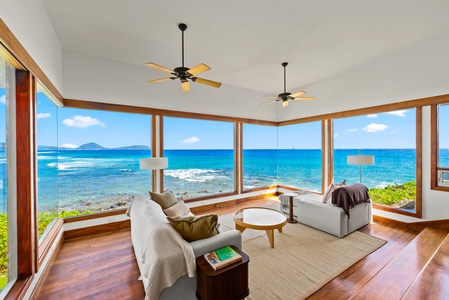 Wake up to panoramic ocean views in your bright living room where floor-to-ceiling windows frame endless blue waters and tropical coastline.