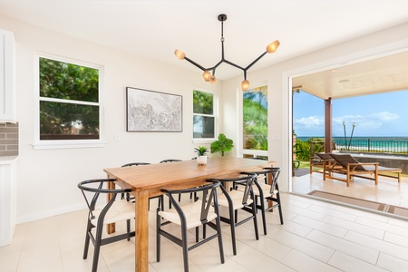 Dining table positioned by windows offering beautiful views of the ocean and lush greenery.