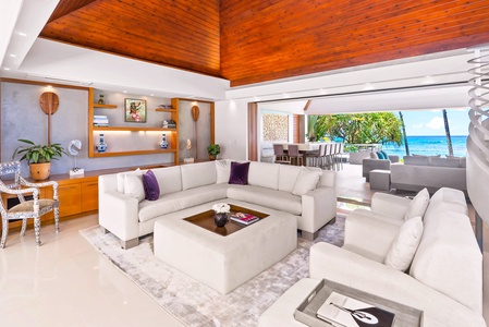 A stunning oceanfront property featuring a sparkling pool, lush lawn, and swaying palms. The pavilion and manicured grounds frame breathtaking views of the Pacific.