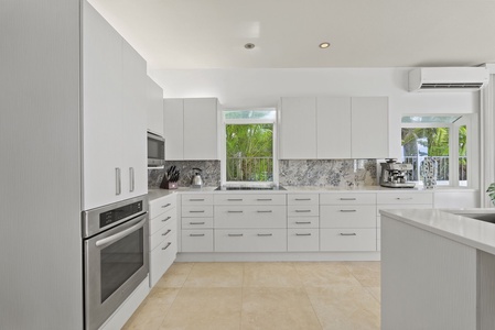 Streamlined white cabinetry, built-in appliances, and marble accents offer a clean, contemporary kitchen aesthetic.