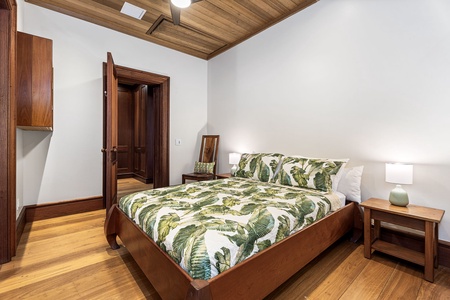 Unwind in your serene bedroom with tropical-print bedding, rich wood details, and warm lighting for peaceful nights.