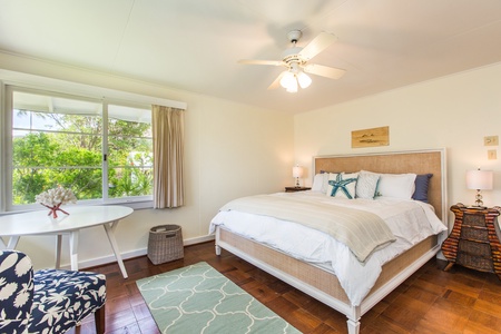 Relax in the spacious primary bedroom with a king bed, natural light, and peaceful garden views.