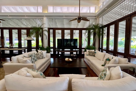 Gather in the spacious living area of the first villa, featuring plush white sectional sofas, a large TV, and a view of the outdoors.