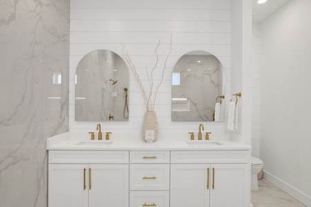 The master bathroom has double vanities and stone counter tops