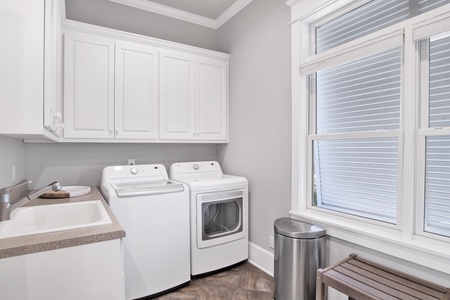 2nd floor laundry room off of the kitchen with a full size washer/dryer and laundry sink