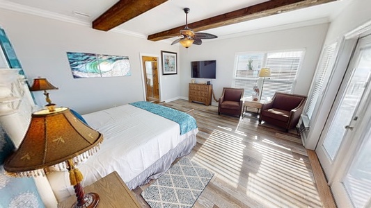 The 1st master bedroom boasts a television, ceiling fan, sitting area and a private bathroom