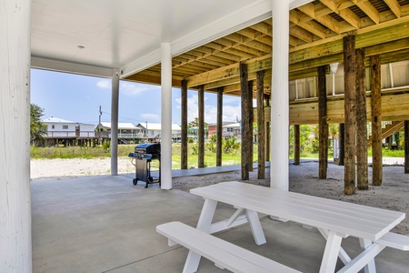 A picnic table and propane grill available in the carport
