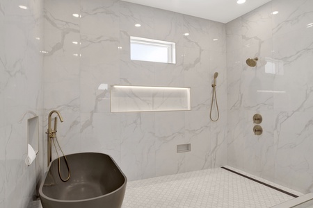 Featuring a walk-in tile shower and a large soaking tub