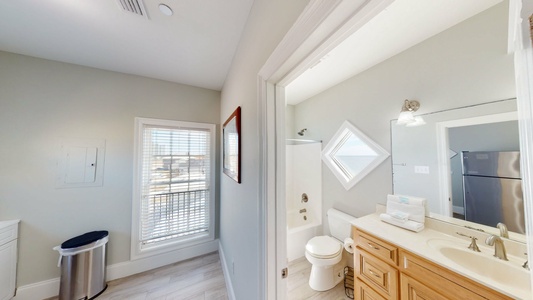 The shared bathroom is off of a room that has a sink and additional refrigerator