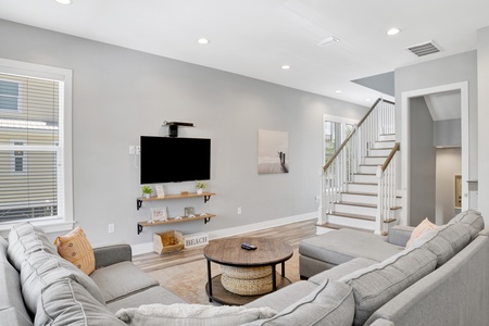 The living room features a TV, balcony access and sectional sofa