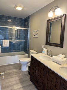 Hallway bathroom features double vanities and tub/shower combo