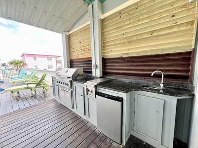 The outdoor kitchenette offers a propane grill, cooktop, mini fridge and sink