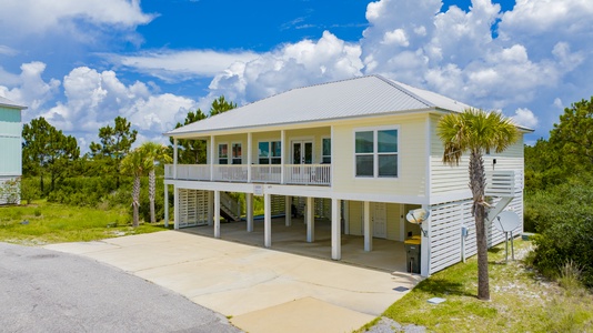 Covered parking underneath the home, with additional parking in the driveway
