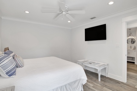 Bedroom 2 has a mounted TV, ceiling fan and shared the 2nd floor bathroom