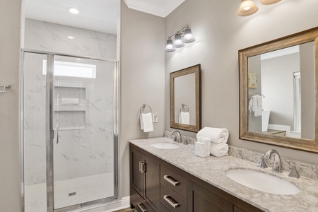 The private bathroom has dual vanities and a walk-in tile shower