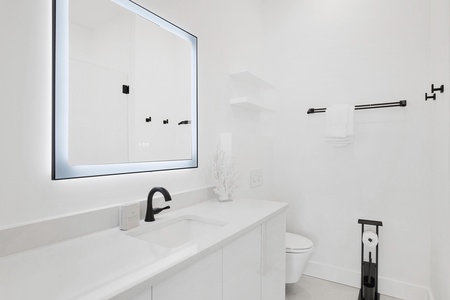 The private bathroom offers a single vanity and LED mirror