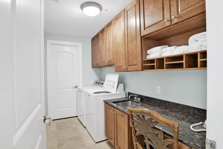Full size washer and dryer in the laundry room with a sink
