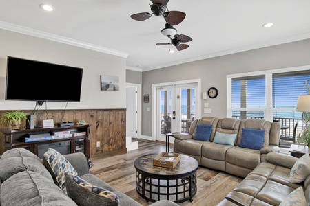 The living room has comfortable seating, balcony access and a TV