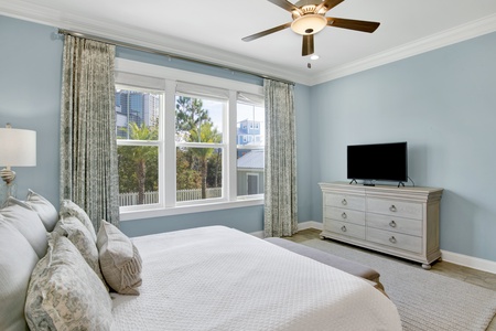 The master suite has a ceiling fan and large mounted TV