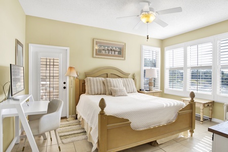 The master bedroom has a king bed, TV, ceiling fan and patio access