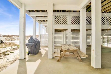 Charcoal grill and picnic table under the home