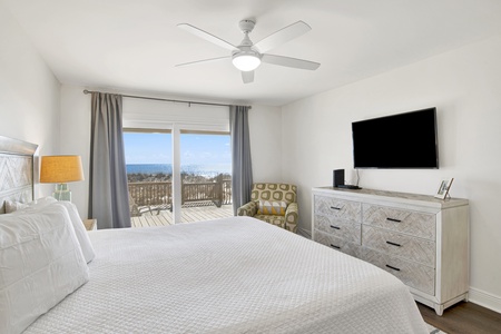 The master bedroom has access to the deck, ceiling fan and a television