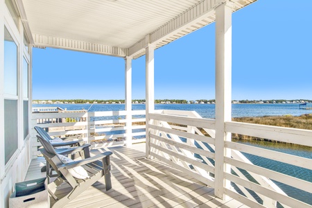 Stairs from the deck lead down to the front of the home and sandy area