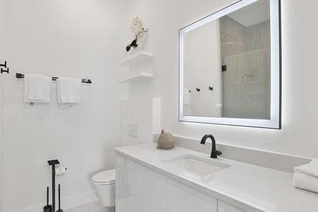 The private bathroom offers a single vanity and LED mirror