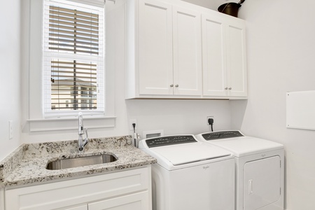Full size washer and dryer with a sink in the laundry room