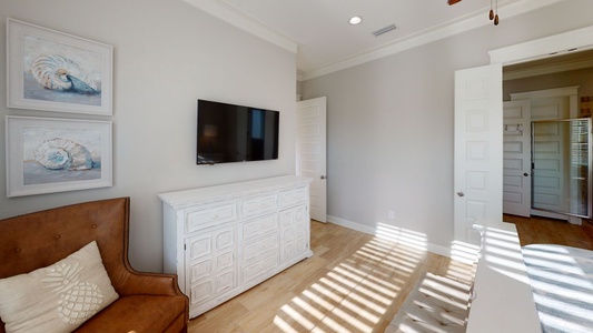 The master suite has a ceiling fan and large mounted TV