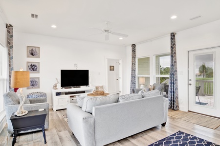 The living room features a TV and balcony access