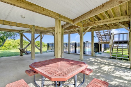 Covered outdoor dining and swing overlooking the pool