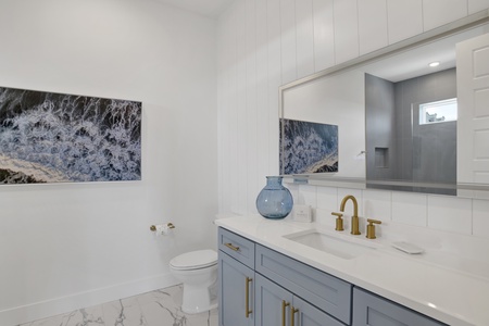 The private bathroom has a single vanity and LED mirror