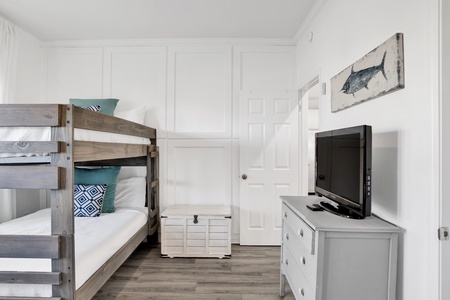 The bunk room has a ceiling fan, TV and an attached bathroom