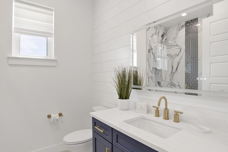 The private bathroom has a single vanity and LED mirror